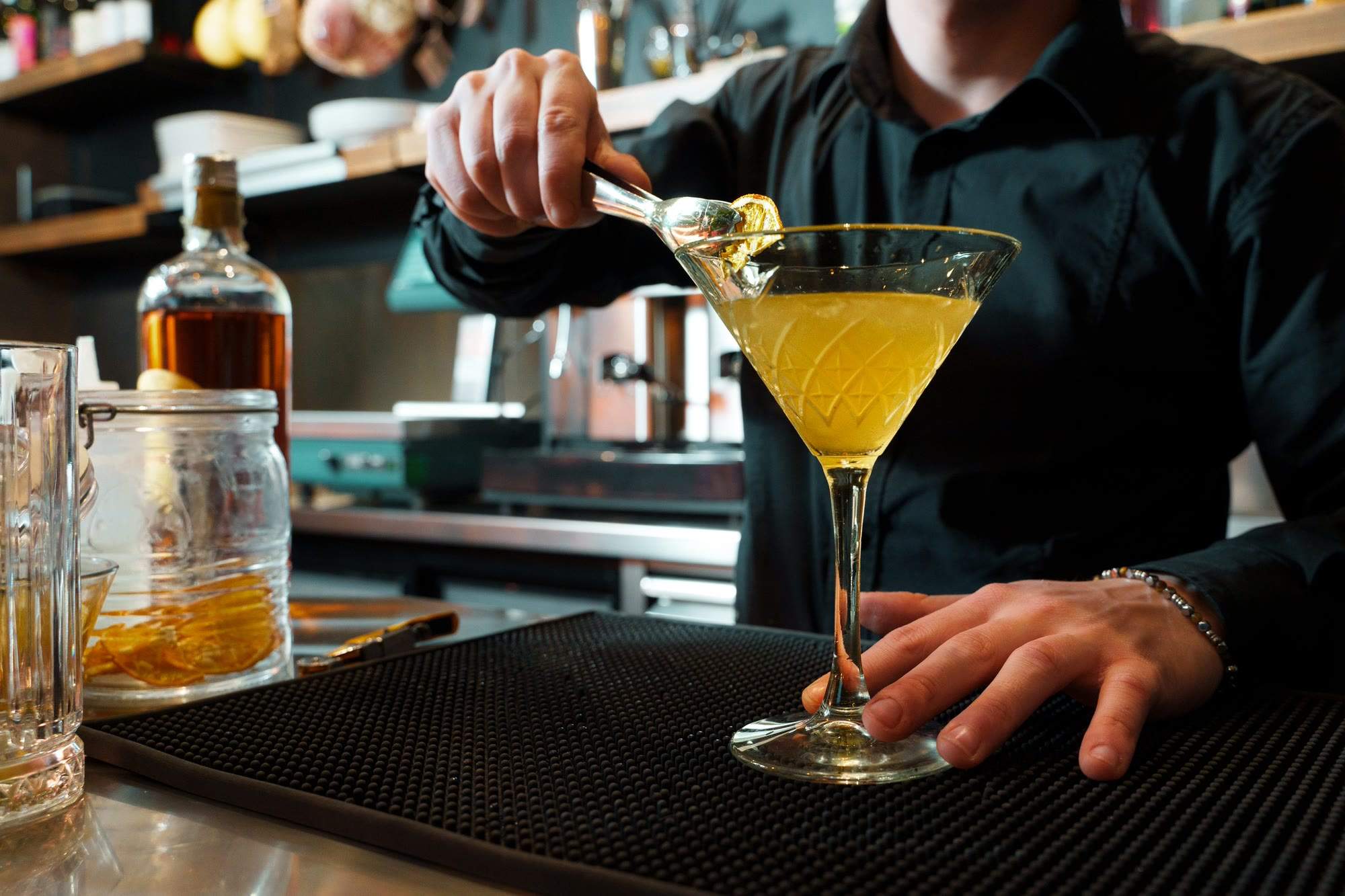 Barkeeper garniert einen Cocktail hinter der Bar